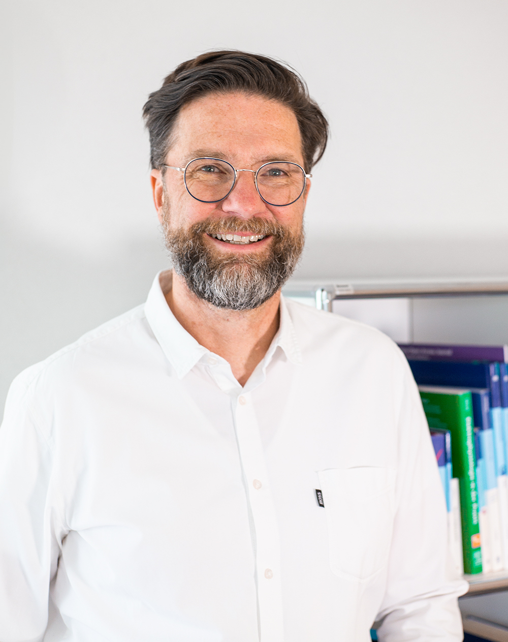 Porträtbild von Stephan Groothuisen vor einem Buchregal